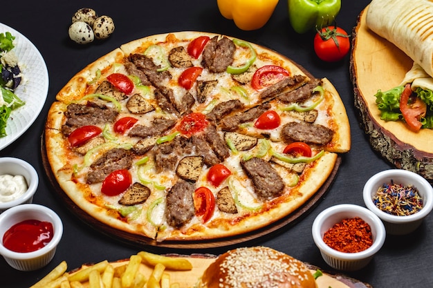 Vista lateral pizza de berenjenas con rodajas a la parrilla de carne roja tomate berenjenas queso y pimiento sobre la mesa