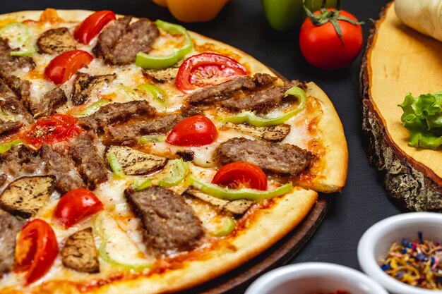Vista lateral pizza de berenjenas con rodajas de queso rojo pimiento y tomate a la parrilla sobre la mesa