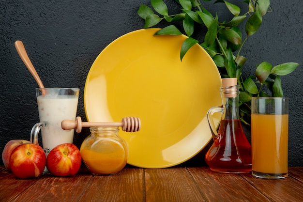 Vista lateral de un plato amarillo vacío y nectarinas frescas maduras con botella de aceite de oliva