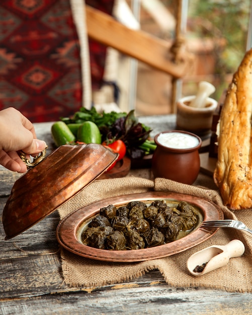 Vista lateral de un plato tradicional azerbaiyano carne dolma de hojas de uva con yogur y verduras