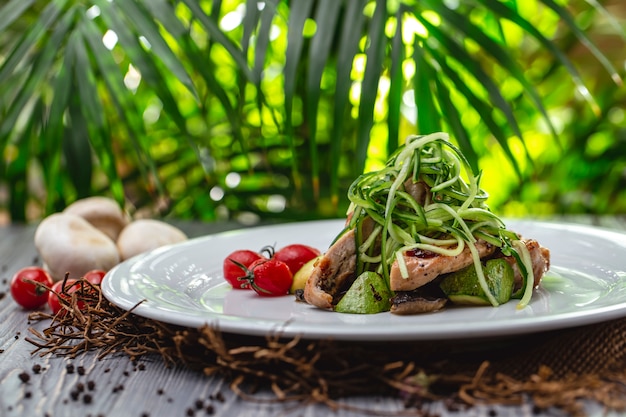 Foto gratuita vista lateral de pollo a la parrilla con tomate, calabacín, champiñones y pepino en un plato