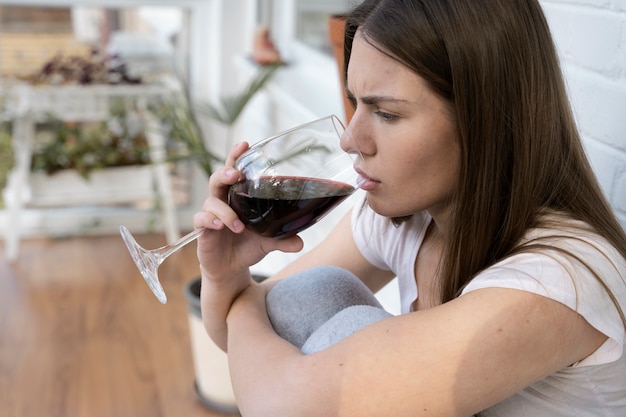 Vista lateral preocupada mujer bebiendo vino