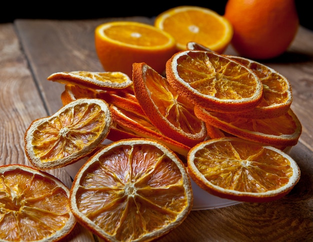Vista lateral de primer plano de naranja seca y naranjas frescas en la mesa de madera