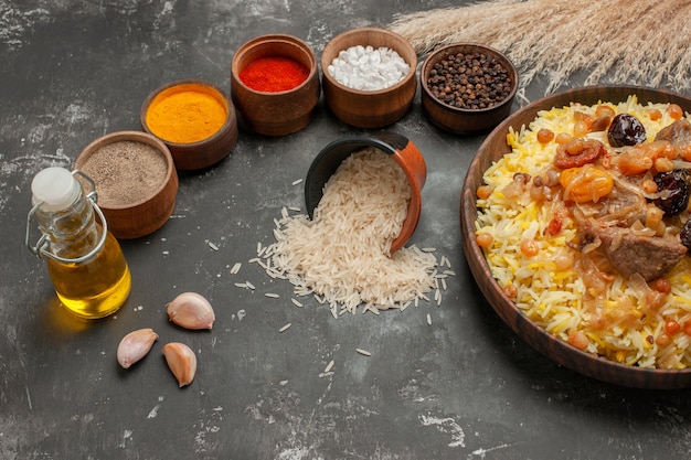 Vista lateral de primer plano pilaf de arroz con tazones de carne de especias y arroz botella de aceite de ajo