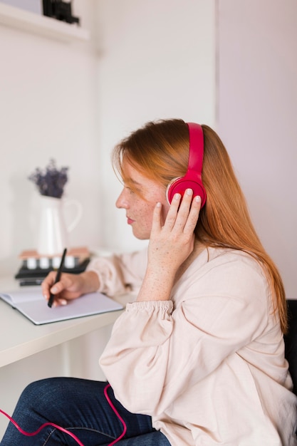 Vista lateral de la profesora con auriculares sosteniendo un curso en línea