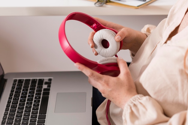 Vista lateral de la profesora sosteniendo auriculares y portátil para clase en línea