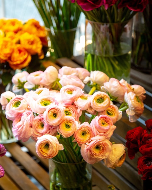 Vista lateral del ramo de flores de ranúnculo rosa en florero de vidrio en la tienda de flores