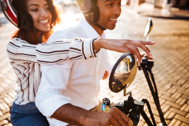 Vista lateral recortada de la feliz pareja africana monta en moto moderna en la calle