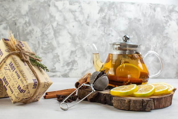 Vista lateral del regalo de té negro con limones de limón y canela en una bandeja de madera en el cuadro blanco