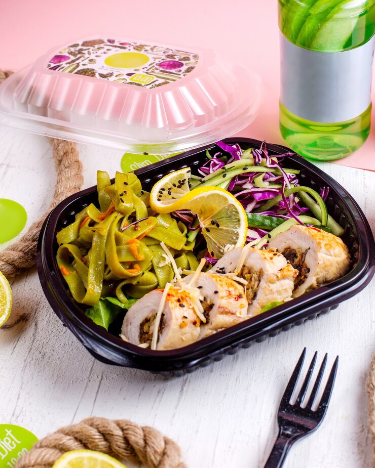 Foto gratuito vista lateral del rollo de pollo relleno con ajo vegetal y nueces servido con ensalada de repollo en la caja de entrega