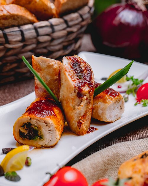 Vista lateral del rollo de pollo con verduras rellenas y una rodaja de limón