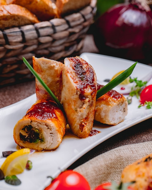 Vista lateral del rollo de pollo con verduras rellenas y una rodaja de limón