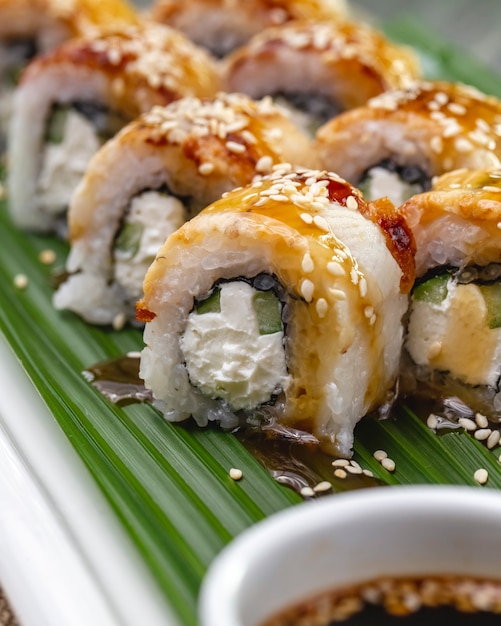 Vista lateral rollo de sushi de salmón al horno con pepino de queso crema nori y semillas de sésamo