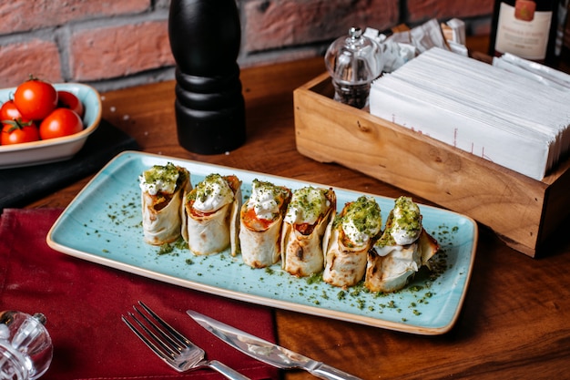 Foto gratuita vista lateral de rollos de lavash con salsa agria de verduras y pistachos en una mesa de madera