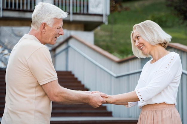 Foto gratuita vista lateral de la romántica y amorosa pareja senior cogidos de la mano al aire libre