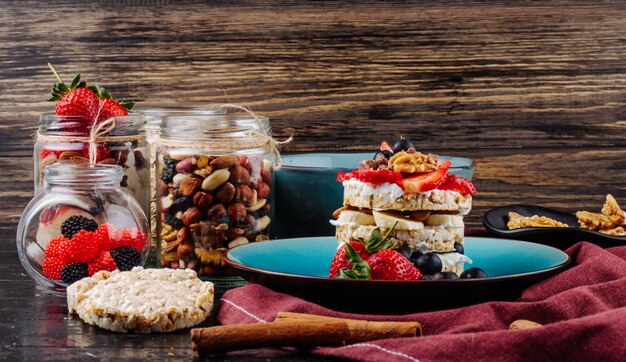 Vista lateral de sabroso pan crujiente con arándanos maduros, fresas y nueces con crema agria en un plato de cerámica