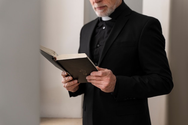 Vista lateral del sacerdote mayor leyendo la biblia