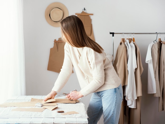 Foto gratuita vista lateral del sastre femenino en el estudio con ropa