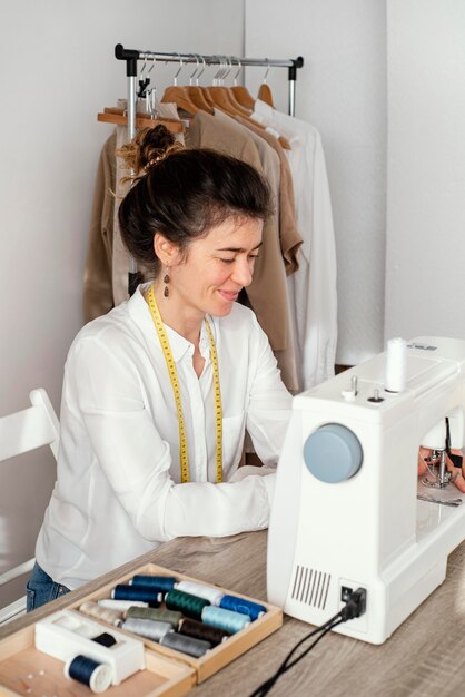 Vista lateral del sastre femenino trabajando con máquina de coser