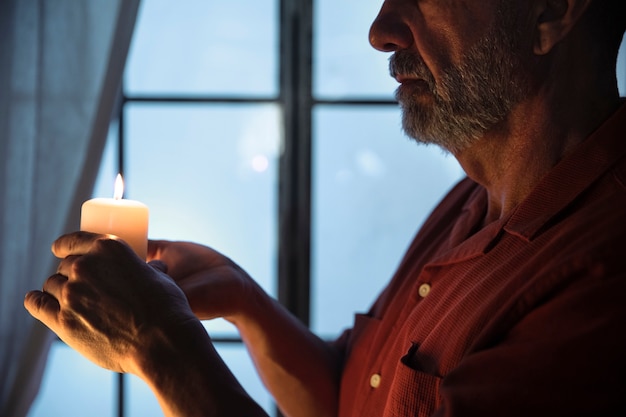 Foto gratuita vista lateral senior hombre sosteniendo vela encendida