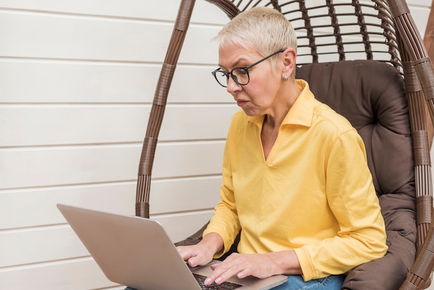 Foto gratuita vista lateral senior mujer trabajando en su computadora portátil