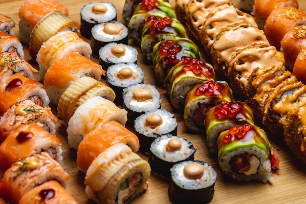 Vista lateral set de sushi philadelphia roll con salmón y congrio ell maki dragon roll y hot roll en un tablero