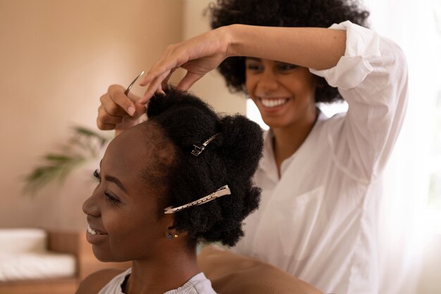 Vista lateral sonriente estilista arreglando el cabello