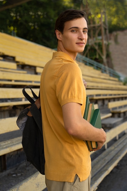 Foto gratuita vista lateral sonriente hombre cargando libros