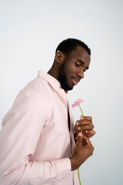 Vista lateral sonriente hombre sosteniendo flor