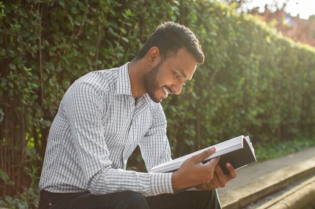 Vista lateral sonriente hombre sosteniendo libro