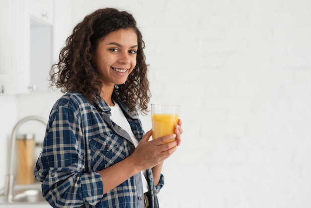 Vista lateral sonriente mujer bebiendo jugo de naranja