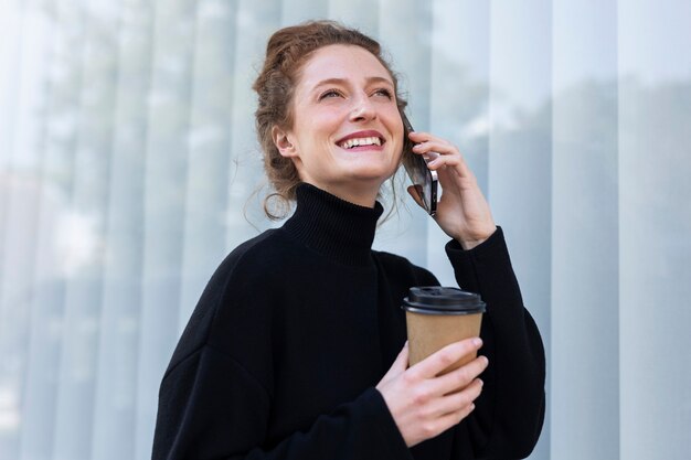 Vista lateral sonriente mujer de negocios hablando por teléfono