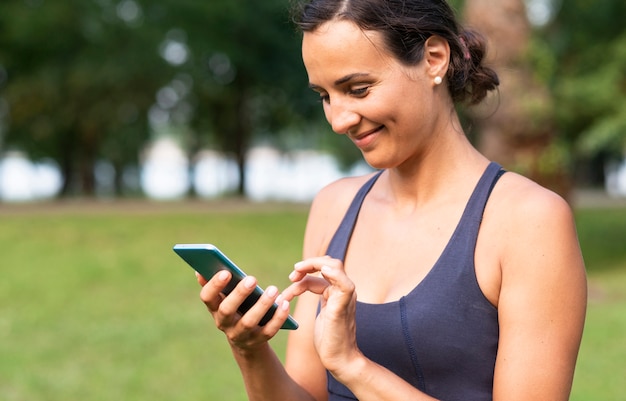 Vista lateral sonriente mujer con smartphone