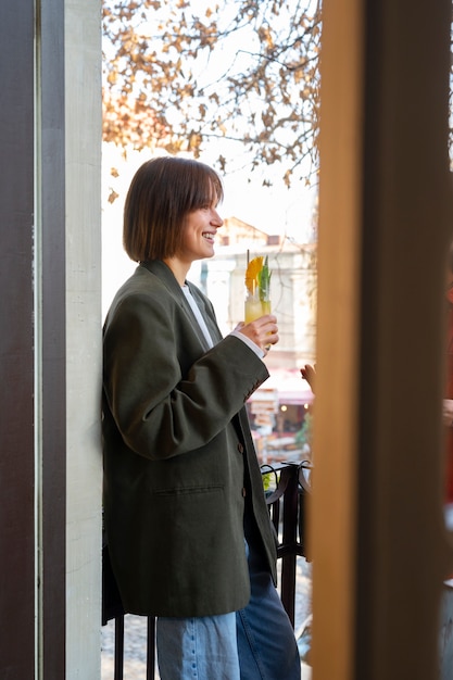 Foto gratuita vista lateral sonriente mujer sosteniendo cóctel