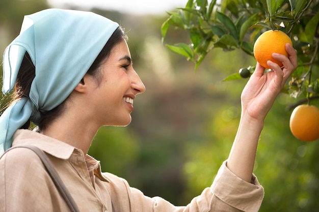 Vista lateral sonriente mujer sosteniendo fruta