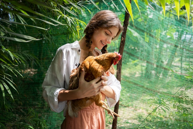 Vista lateral sonriente mujer sosteniendo gallina