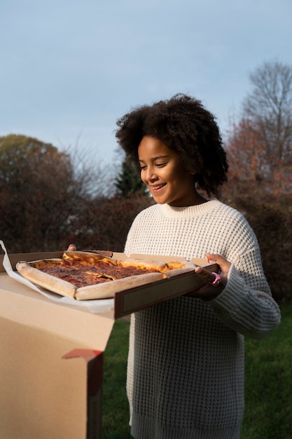 Vista lateral sonriente mujer sosteniendo pizza