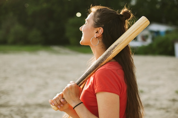 Foto gratuita vista lateral sonriente niña sosteniendo un bate de béisbol