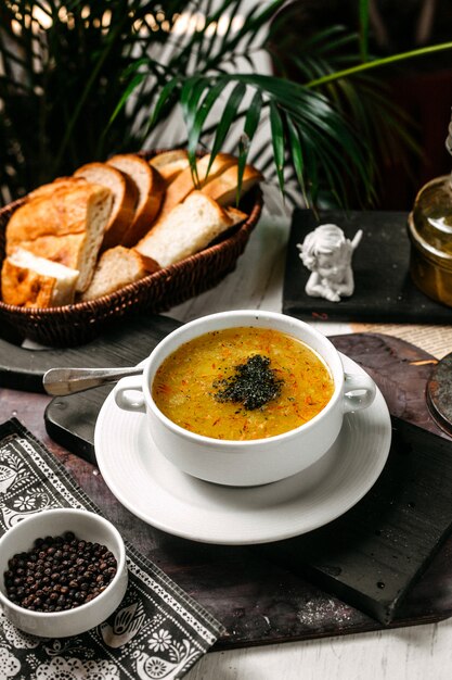 Vista lateral de sopa de guisantes y lentejas con azafrán y hierbas en un tazón blanco