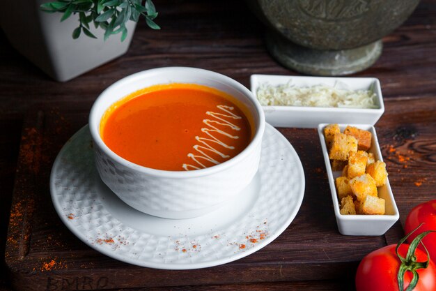 Vista lateral sopa de tomate en mesa de madera