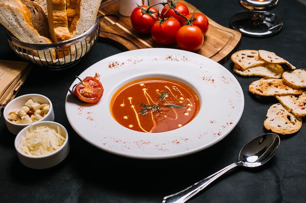 Vista lateral sopa de tomate con queso y galletas