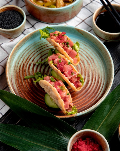 Foto gratuita vista lateral de tacos de salmón con caviar rojo y cebolla verde en un plato