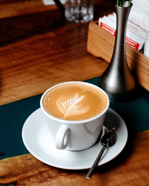 Vista lateral de una taza de café con leche en la mesa de madera