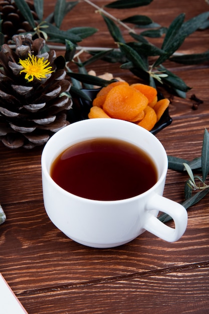 Foto gratuita vista lateral de una taza de té con albaricoques secos en madera