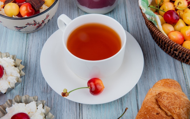 Vista lateral de una taza de té con cerezas maduras lluviosas en rústico
