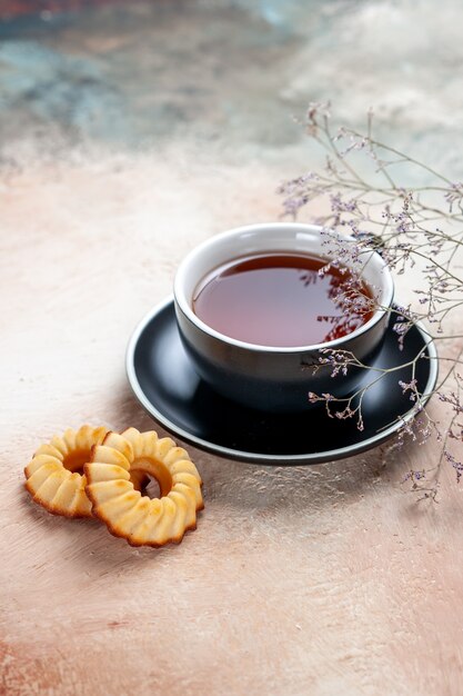 Vista lateral de una taza de té negro taza de té galletas ramas de los árboles