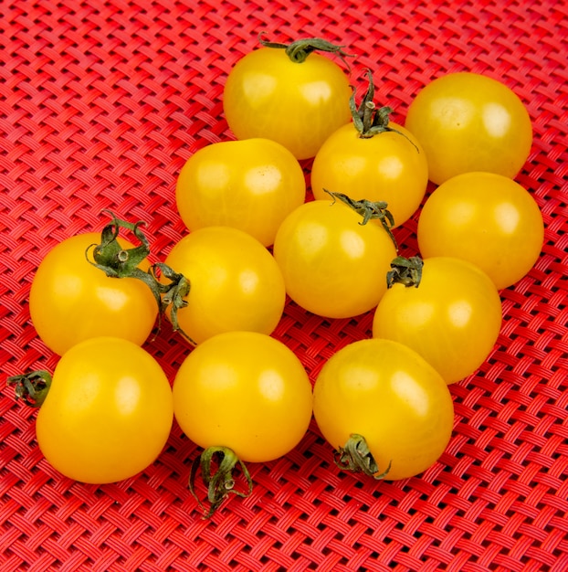 Vista lateral de tomates amarillos sobre superficie de tela roja