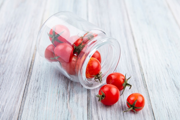 Foto gratuita vista lateral de los tomates que se derraman fuera de la jarra sobre madera