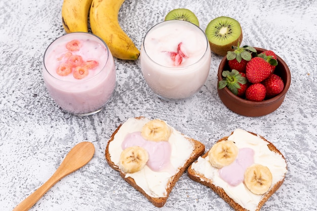 Vista lateral de tostadas con yogurt y frutas en superficie blanca horizontal