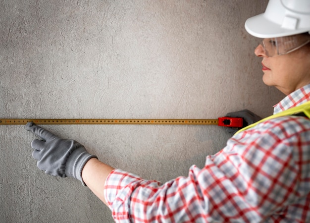 Foto gratuita vista lateral del trabajador de la construcción femenina con casco y cinta métrica